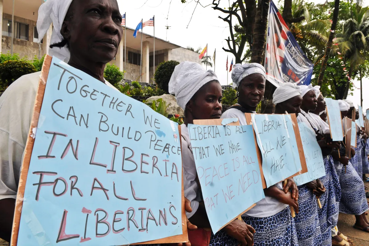 Members of the Women in Peacebuilding Network (WIPNET) carry placards with messages of peace and non-violence during the 2011 elections in Liberia. UN Photo/Emmanuel Tobey Women standing in a line holding hand written placards with messages for peace.